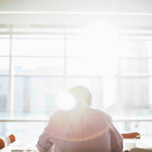Professional man working in conference room with sun shining through window