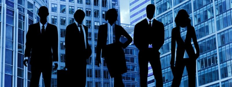 Silhouette of professionals in front of office buildings, to represent the importance of getting the most from your people in order to reduce business costs